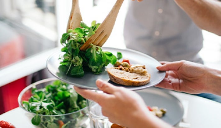 Las verduras y el pan son comidas vegetarianas muy útiles. Una persona sirve una comida vegetariana con verduras y pan.