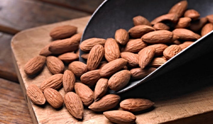 Cuchara y tabla con almendras enteras para pelar Cuchara y tabla con almendras enteras para pelar