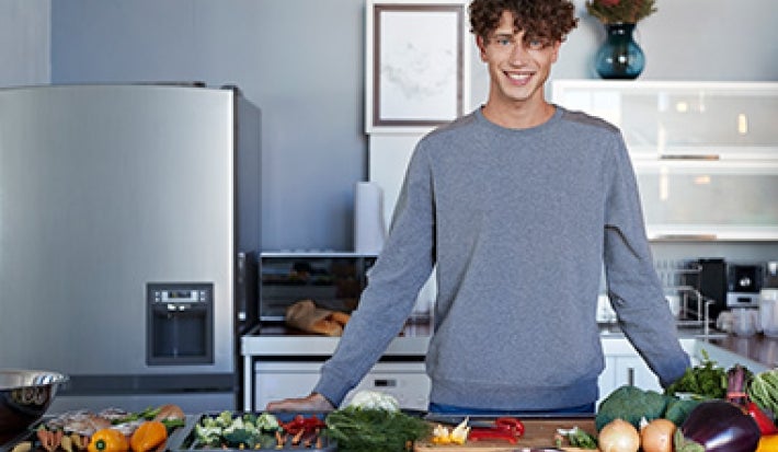 Hombre en cocina con diferentes alimentos, quitar mal olor de la heladera Hombre en cocina con diferentes alimentos, quitar mal olor de la heladera