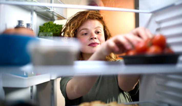 Mujer refrigerando tomates, quitar mal olor de la heladera Mujer refrigerando tomates, quitar mal olor de la heladera