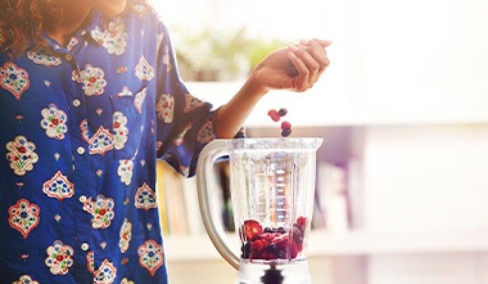 Mujer preparando acaí bowl añadiendo frutas en licuadora Mujer preparando acaí bowl añadiendo frutas en licuadora