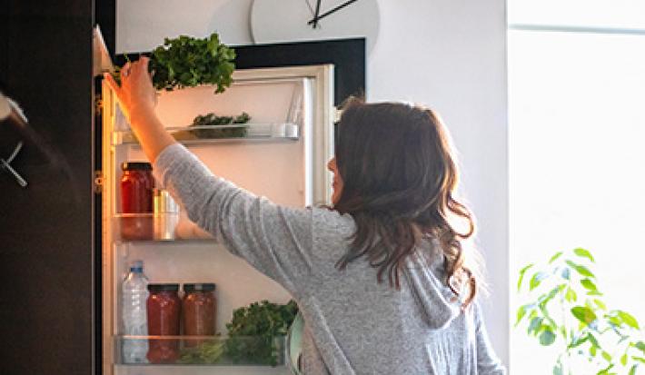 Mujer sacando ingrediente de heladera, quitar mal olor de la heladera Mujer sacando ingrediente de heladera, quitar mal olor de la heladera