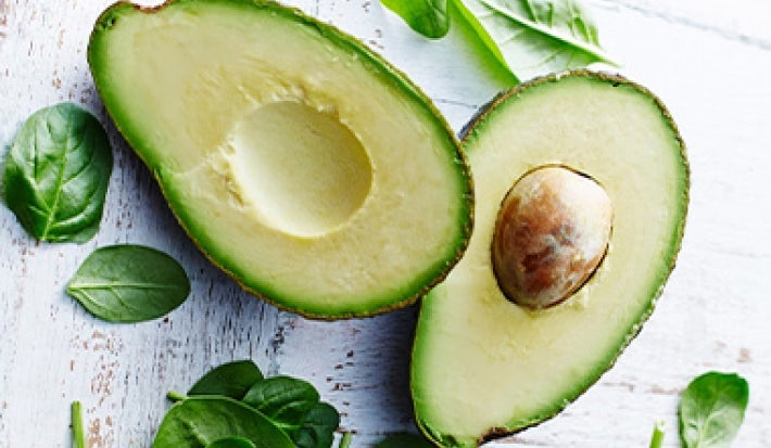 Palta partida por la mitad y hojas de espinaca alimentación balanceada Palta partida por la mitad y hojas de espinaca alimentación balanceada