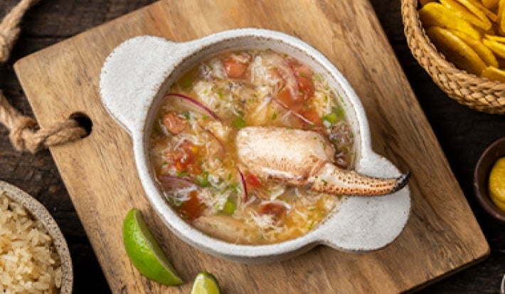 Plato de caldo de pescado con cangrejo, arroz y chips de plátano Plato de caldo de pescado con cangrejo, arroz y chips de plátano